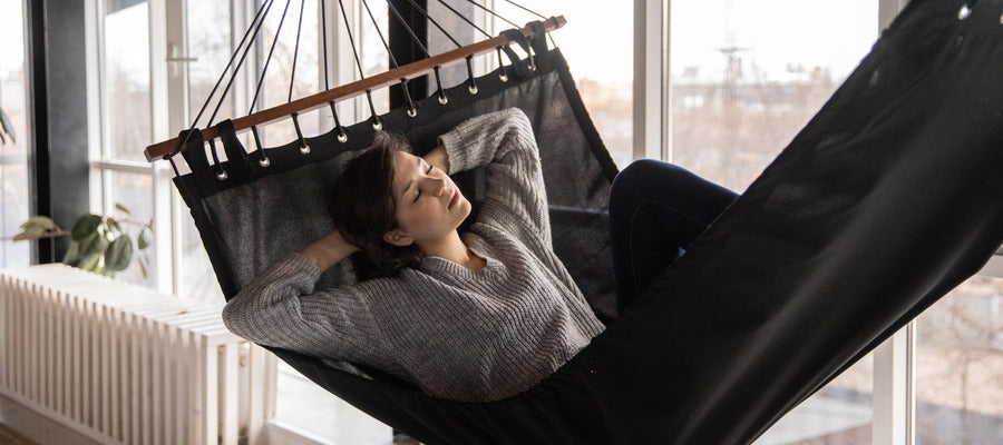 woman taking a nap during daytime in a hammock with hands behind her head