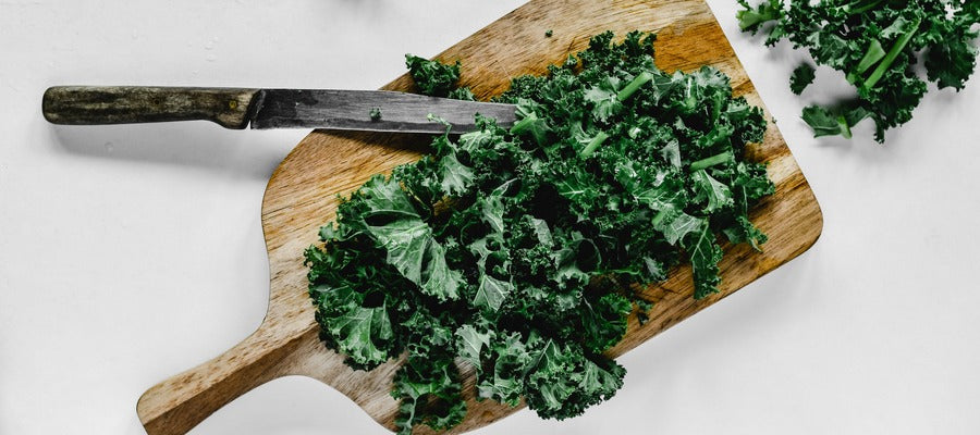 kale on wooden cutting board with knife next to it
