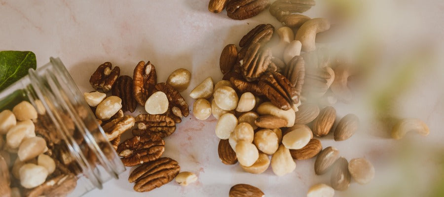 nueces derramadas de un frasco de vidrio sobre una mesa vista desde arriba