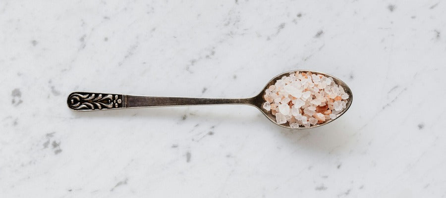 spoonful of Himalayan salt lying on marble countertop