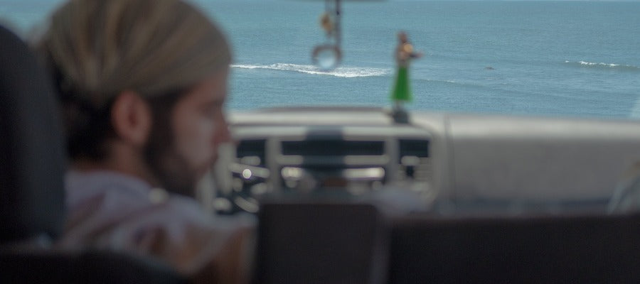 blurry driver looking to the side with blurry dashboard and blue sea in the background