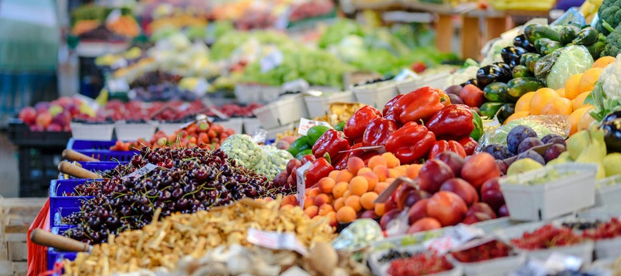 Cajas con frutas y verduras en el mercado vistas desde un lado.