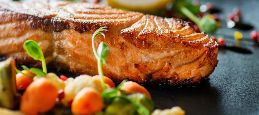 salmón asado en un plato con verduras y otras verduras a su alrededor