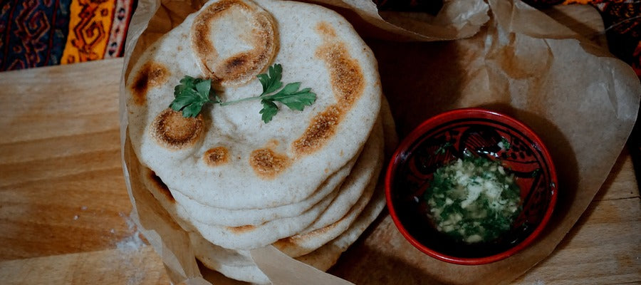 Panes planos naan apilados sobre una mesa con un poco de perejil encima