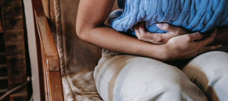 Mujer sosteniendo sus manos sobre su estómago mientras experimenta calambres en el ciclo menstrual.