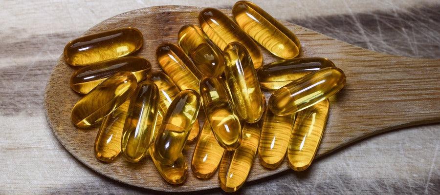 fish oil capsule supplements on a wooden spoon