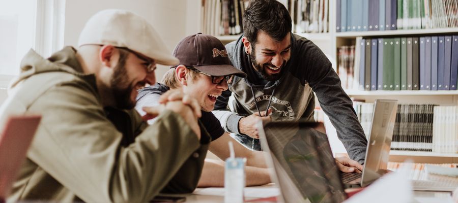 coworkers at a desk looking at a computer and laughing