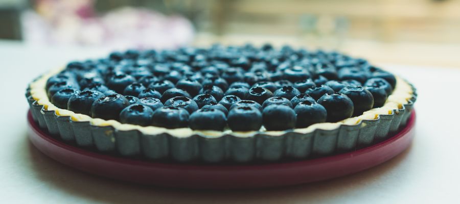 round blueberry pie plate on white table with blurry background