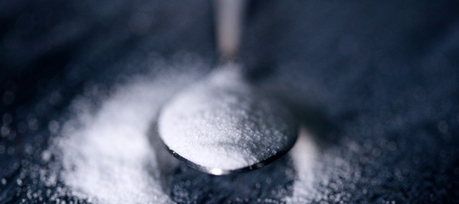 closeup of tablespoon of salt against dark blue background