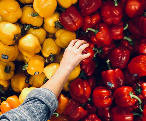 mano recogiendo pimientos rojos frescos