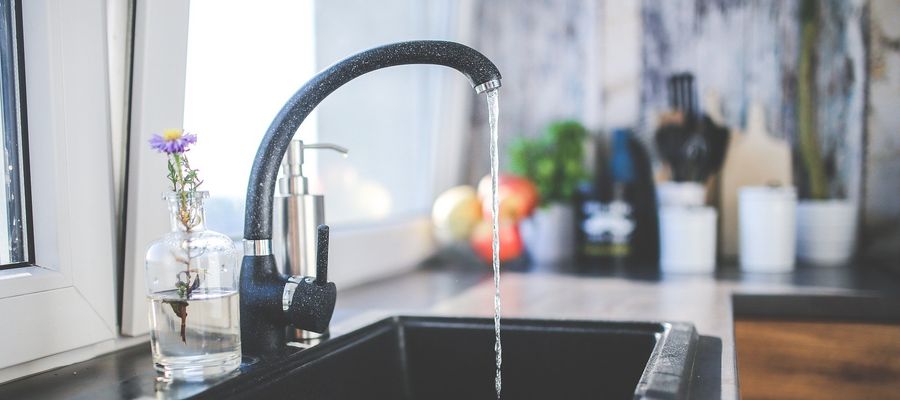 water flowing from black kitchen tap into sink