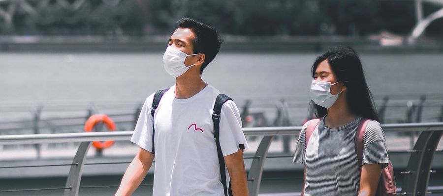 man and woman wearing face masks taking a stroll outside during the day