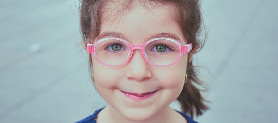 young girl wearing pink eye glasses