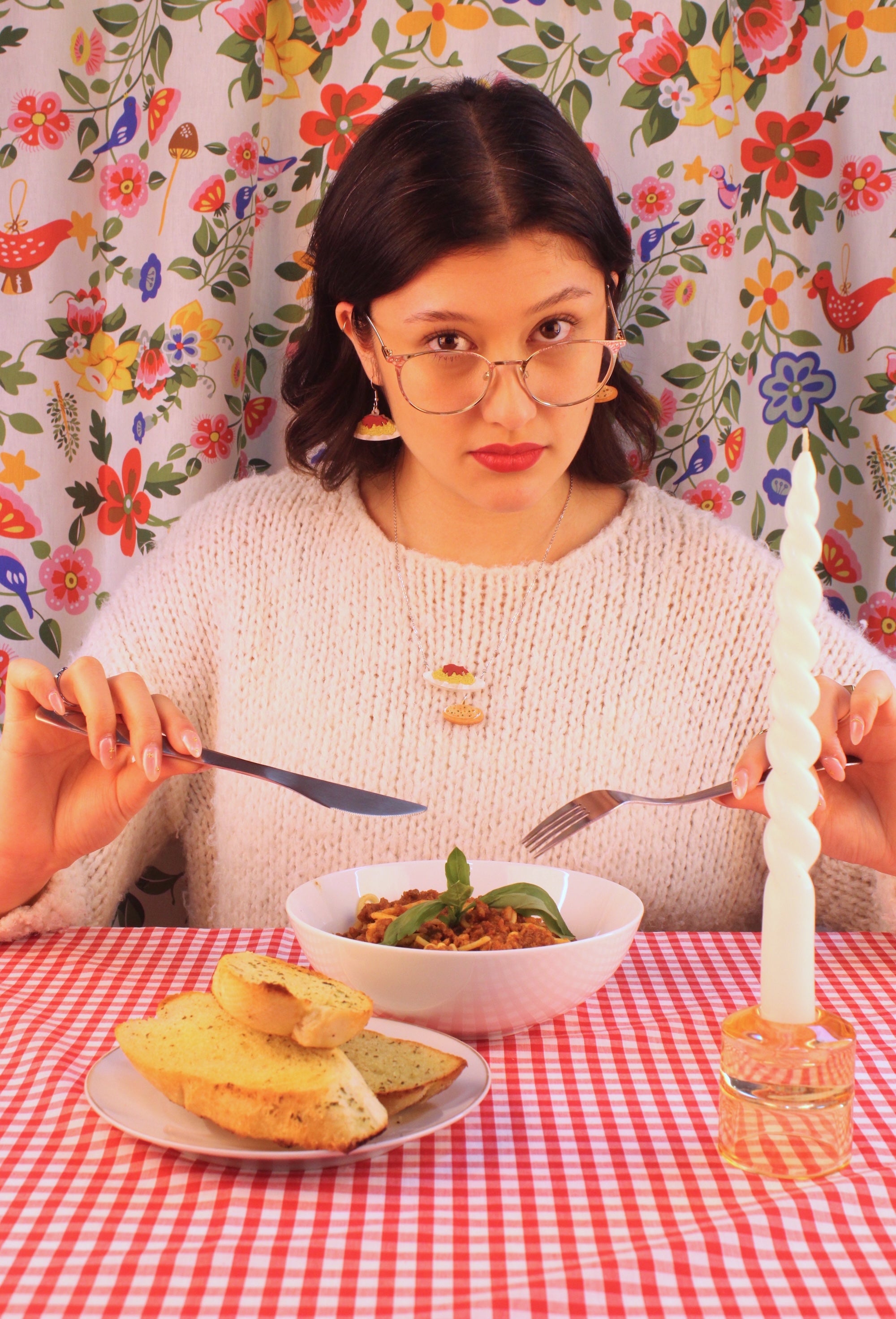 A woman eating spaghetti bolognese wearing spag bol earrings and necklace