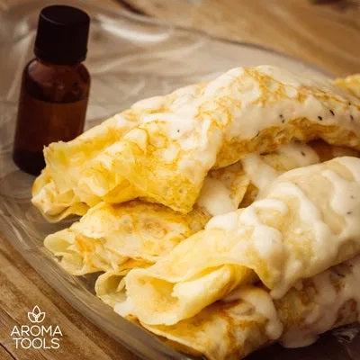 A stack of homemade crepes filled with chicken and drizzled with a milk-based sauce flavored with basil, rosemary and thyme essential oils on a glass platter.