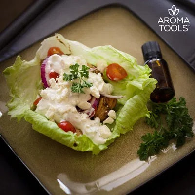 Chicken, grape tomatoes, onions, cheese, olives, and tzatziki flavored with basil, oregano, rosemary, black pepper and dill essential oils in a lettuce wrap on a ceramic plate.