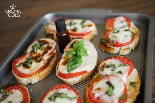 Toasted Margherita Garlic Bread with tomato slices and mozzarella cheese and basil sitting on a baking sheet with an essential oil vial.