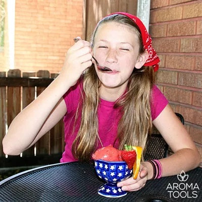 A preteen enjoying a bowl of homemade strawberry and orange essential oil-flavored sorbet outside on a patio.