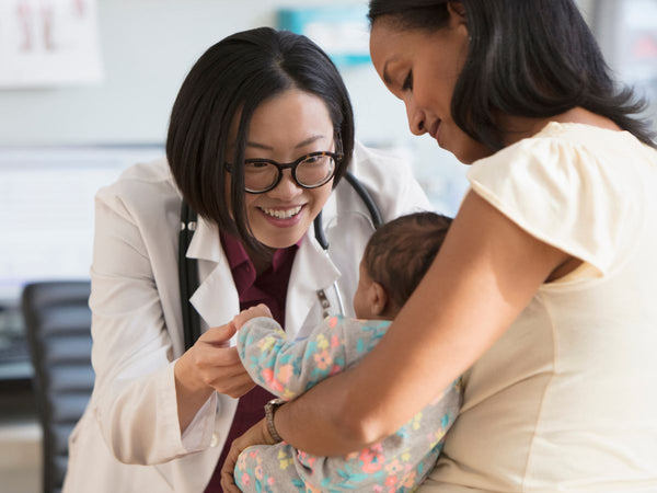 mother holding her baby whilst a doctor is looking at her child