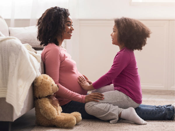 child touching her mother's pregnant belly