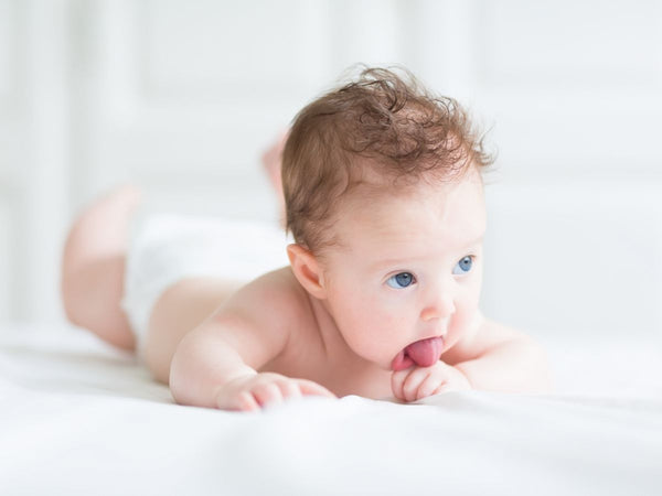 baby rolling on its belly pocking tongue out