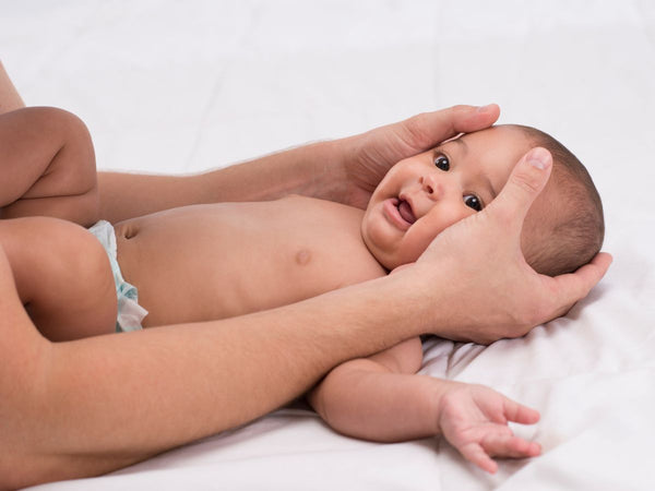 baby lying on its back, a lady is cupping its head