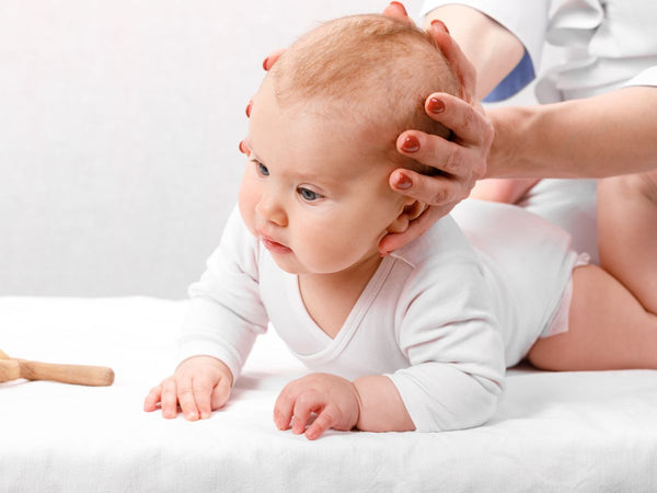 lady holding a baby's head whilst it's crawling