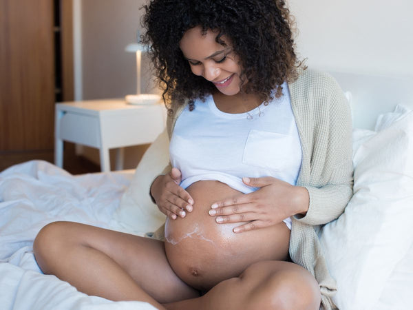 woman rubbing cream onto her pregnant belly