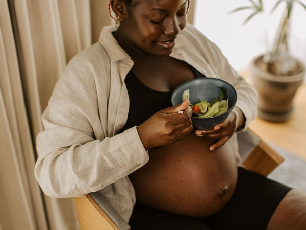 pregnant woman sitting down, eating a salad