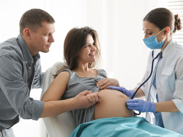 doctor with a stethoscope on a pregnant woman's belly