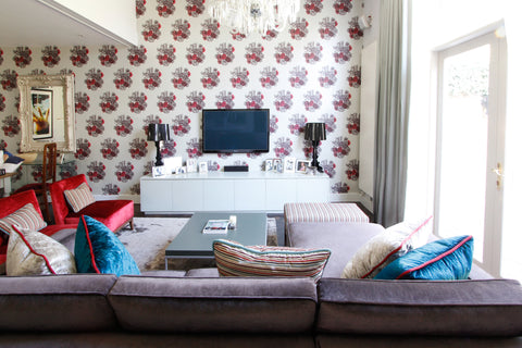 Living room design with feature wall of cole and son wallpaper, romo velvets, the sofa and chair furniture in reds and teals