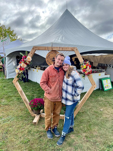 Swan’s Honey employees, Jake (left) and Abby (right), in front of the Swan’s Honey booth at the annual Common Ground Fair. 