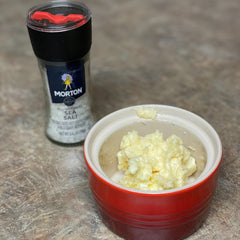 A bowl of handmade honey butter next to a salt shaker.