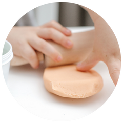 little hands playing with orange dough and wooden rolling pin