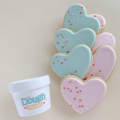 Heart shaped sugar cookies decorated in green and pink beside tub of play dough