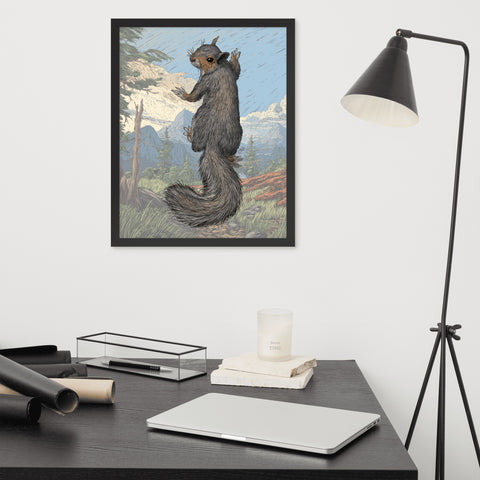 A framed print of a squirrel with its back to us climbing up the print, with a faded landscape in the background.  The print is hanging on the wall over a cluttered desk, with a lamp to the right.