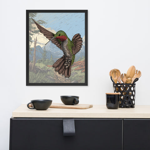 A framed art print with a hand drawn hummingbird in front of a faded background.  The print hangs on a white wall over a counter top with bowls, a coffee cup, and wooden spoons.