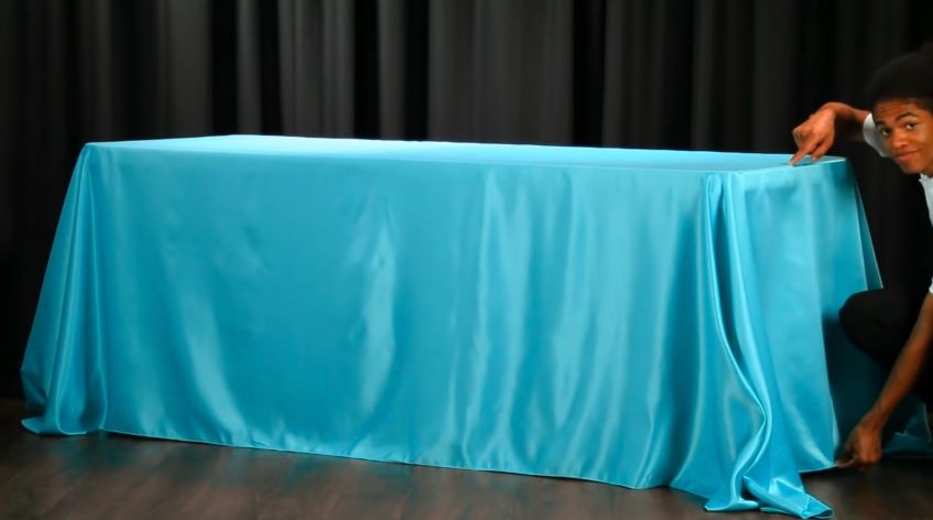 Lift the middle part of the tablecloth on both sides