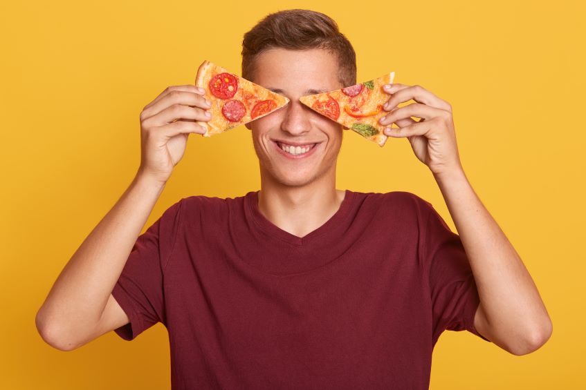 young man holding two pieces of fresh pizza
