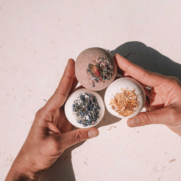 Hands holding handmade Bath Bombs decorated with dried flowers. 