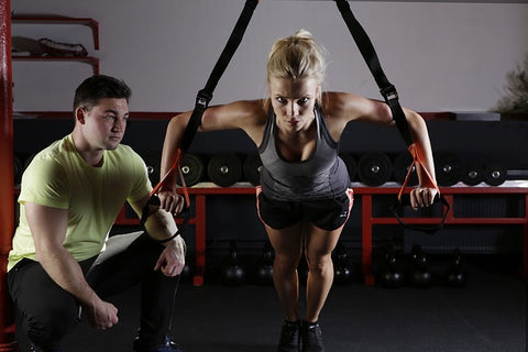 A woman working on muscle building with her trainer.