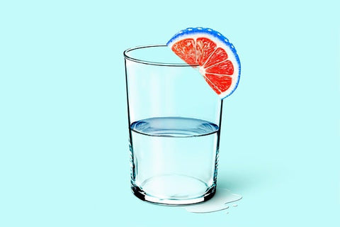 A water glass with a funky citrus wedge that has red fruit and a blue rind on a teal background
