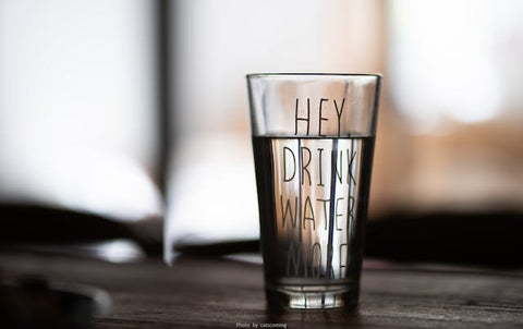 A glass that says 'Hey drink water more!'