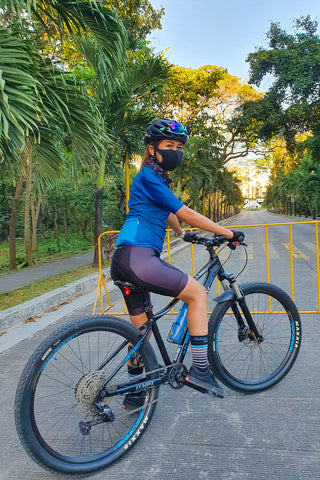 Thea poses with her bike wearing the Women's Cerulean Cycling Jersey