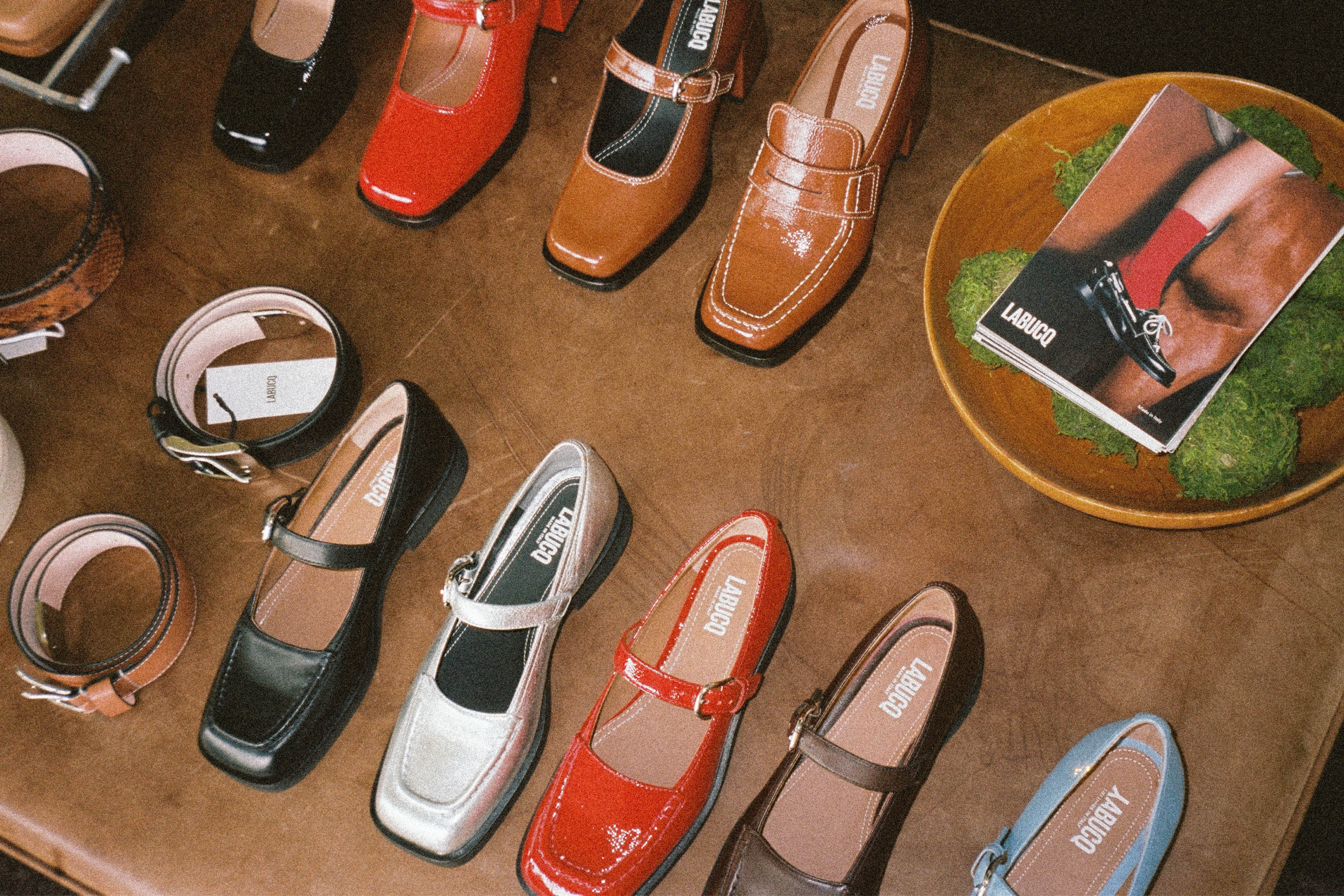 A collection of colorful shoes and belts displayed on a brown table.