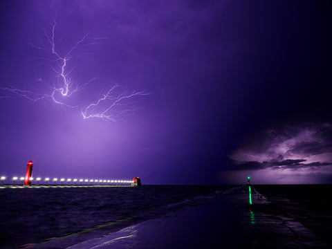 Lightning strikes coastal area with lighthouse