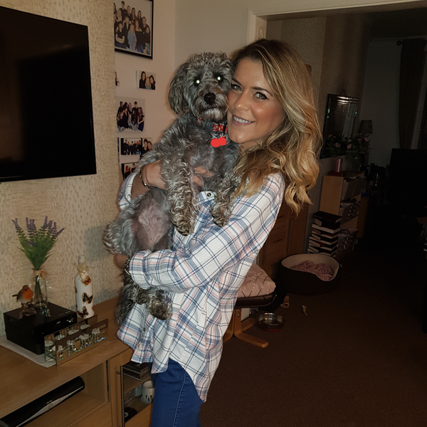 Gemma oaten stands, holding her grey dog Ruby Tuesday