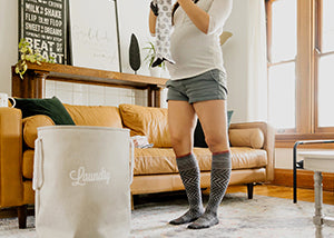 Woman standing in a living room folding baby clothes