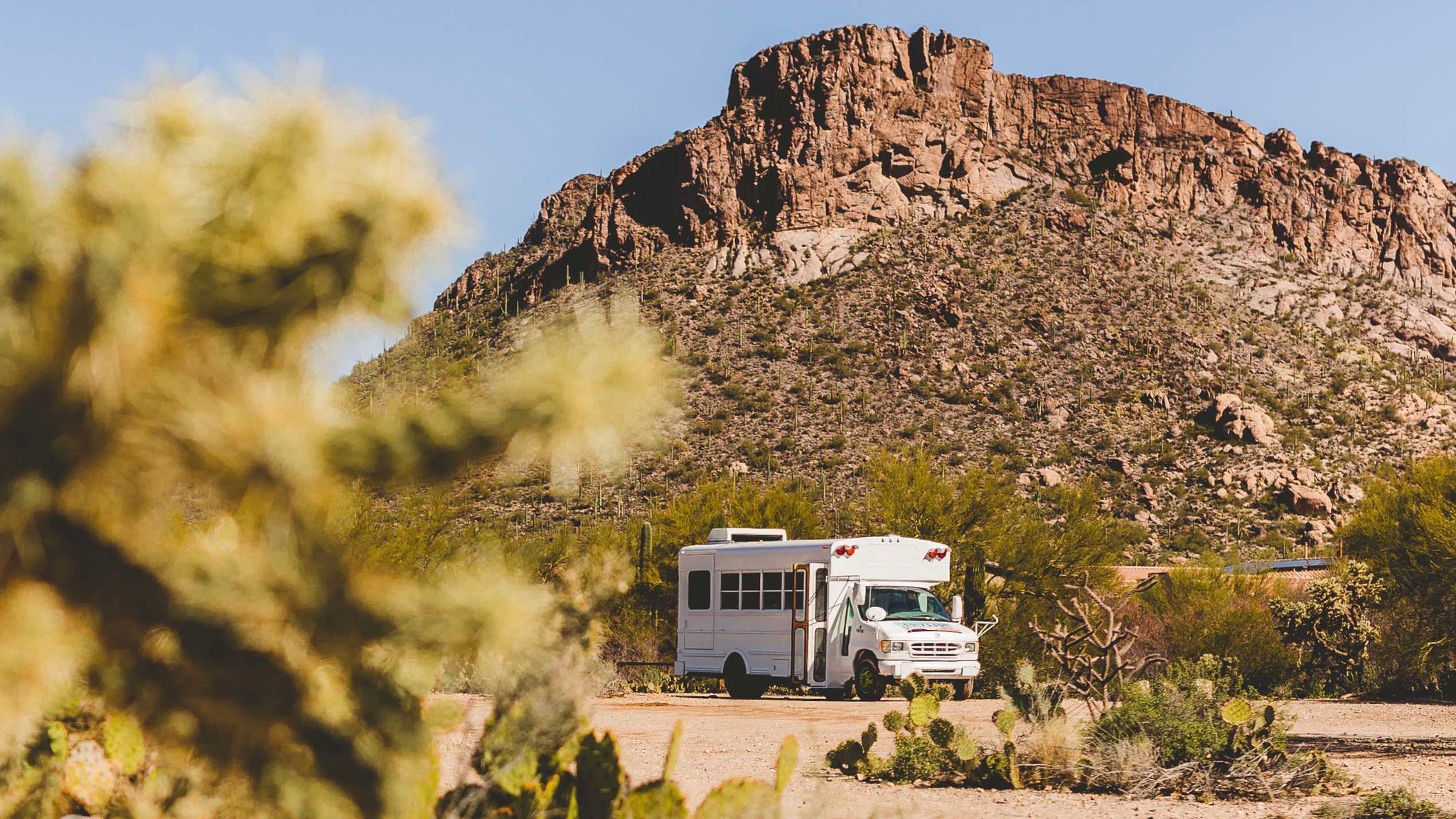 Erixaart mobile shop, photo of white school bus in desert with mountains. Picture is located in Tucson, AZ.