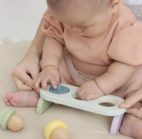 Baby using Montessori-inspired fine motor toy